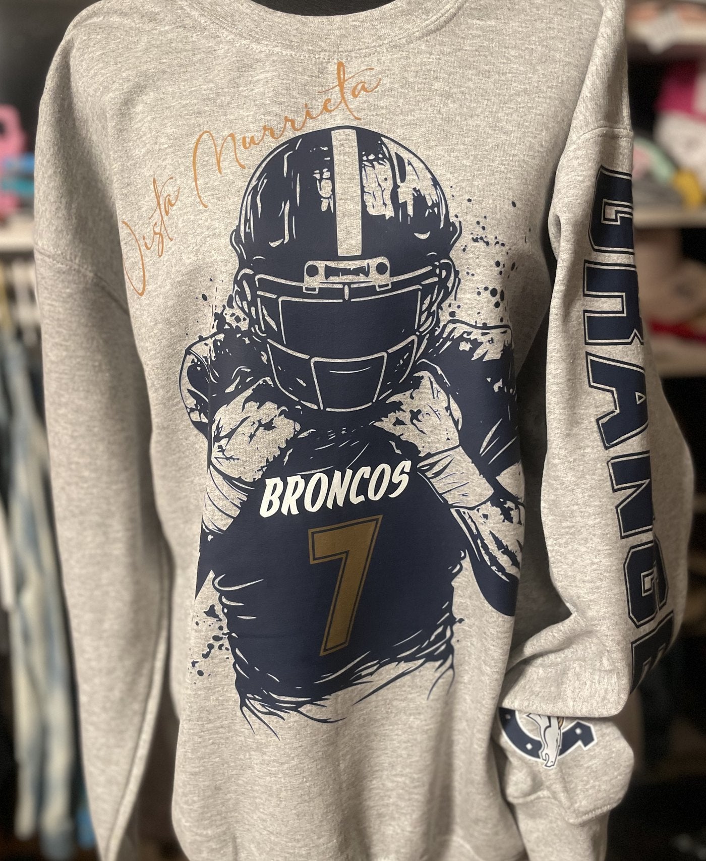 Grey embroidered crewneck with Broncos helmet graphic and name on the sleeve