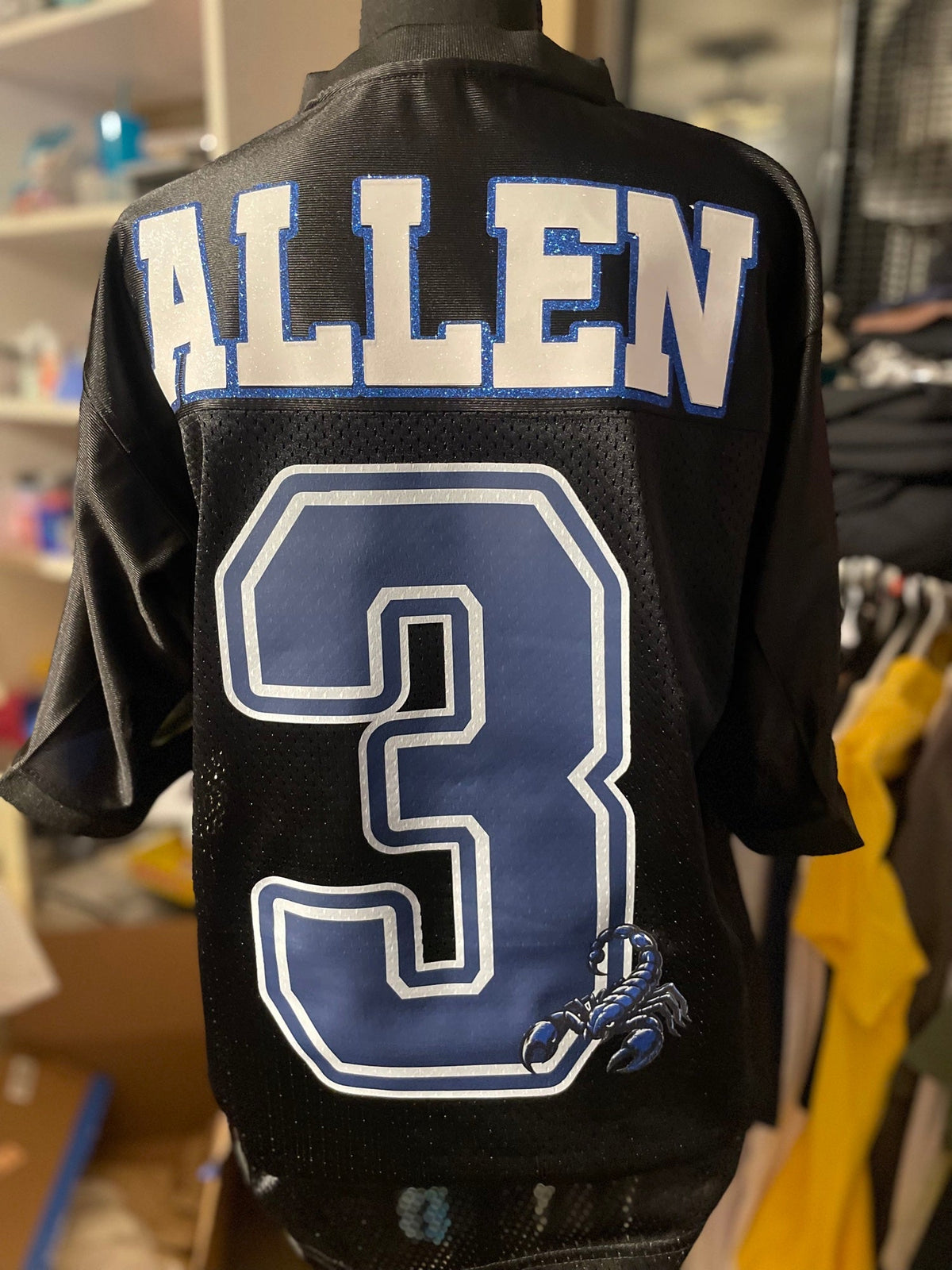 Back of a black custom mesh football jersey with a name and number in blue